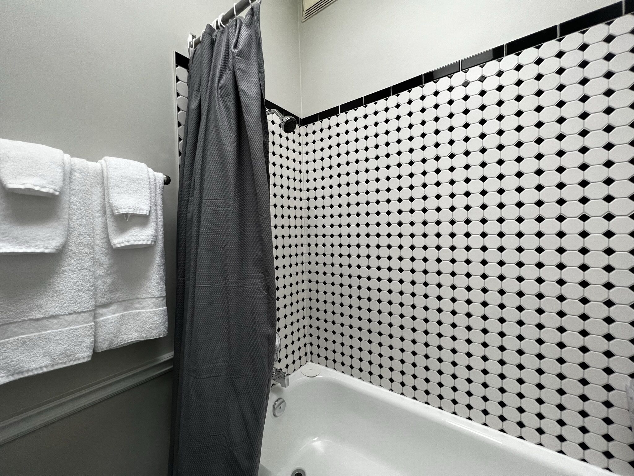 A bathroom with a bathtub, a shower curtain, and a tiled wall with a geometric pattern.
