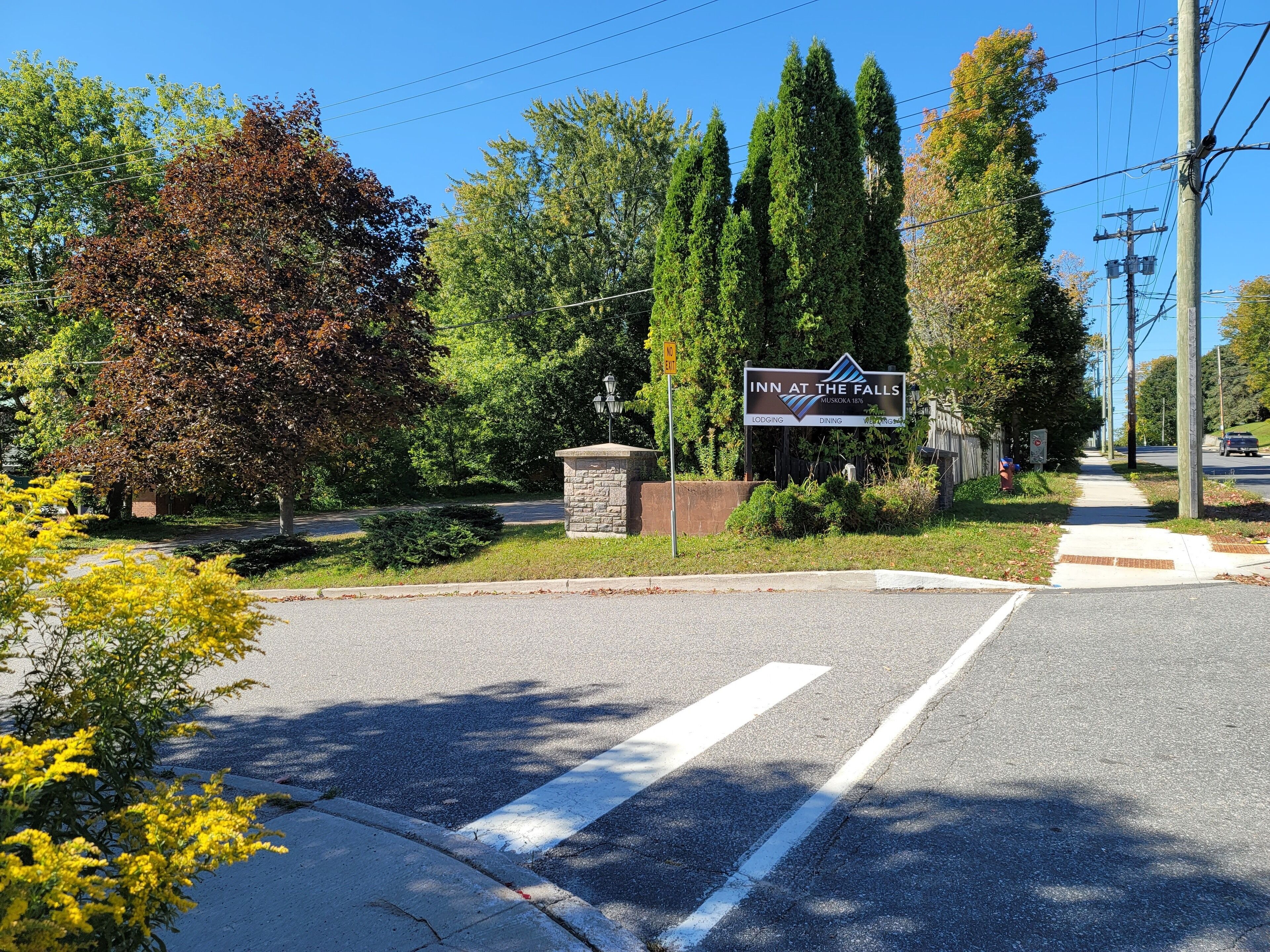 A road sign for 'Inn at the Falls' with a stone base and a lamp post.