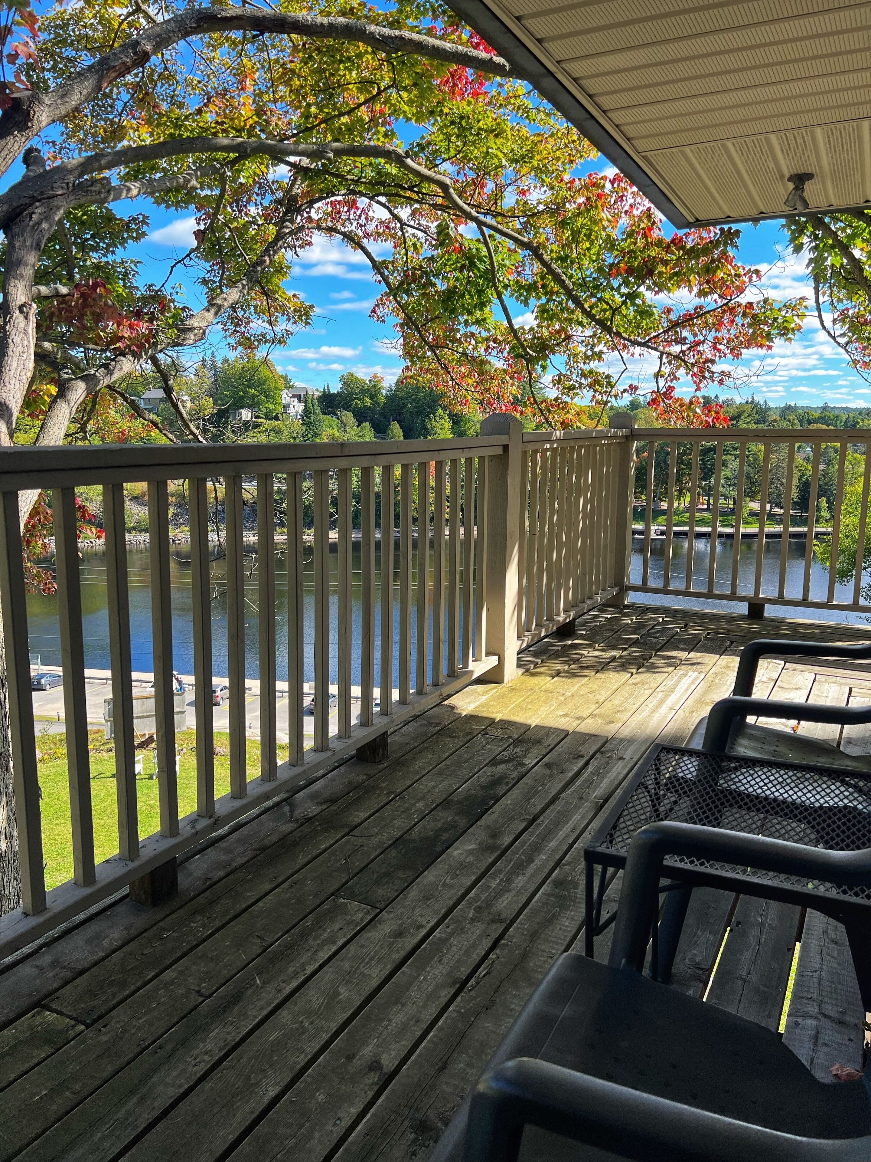 A wooden deck with a railing overlooking a body of water, with trees in the background.