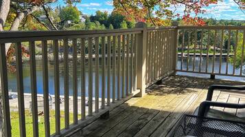 A wooden deck with a railing overlooking a body of water, with trees in the background.