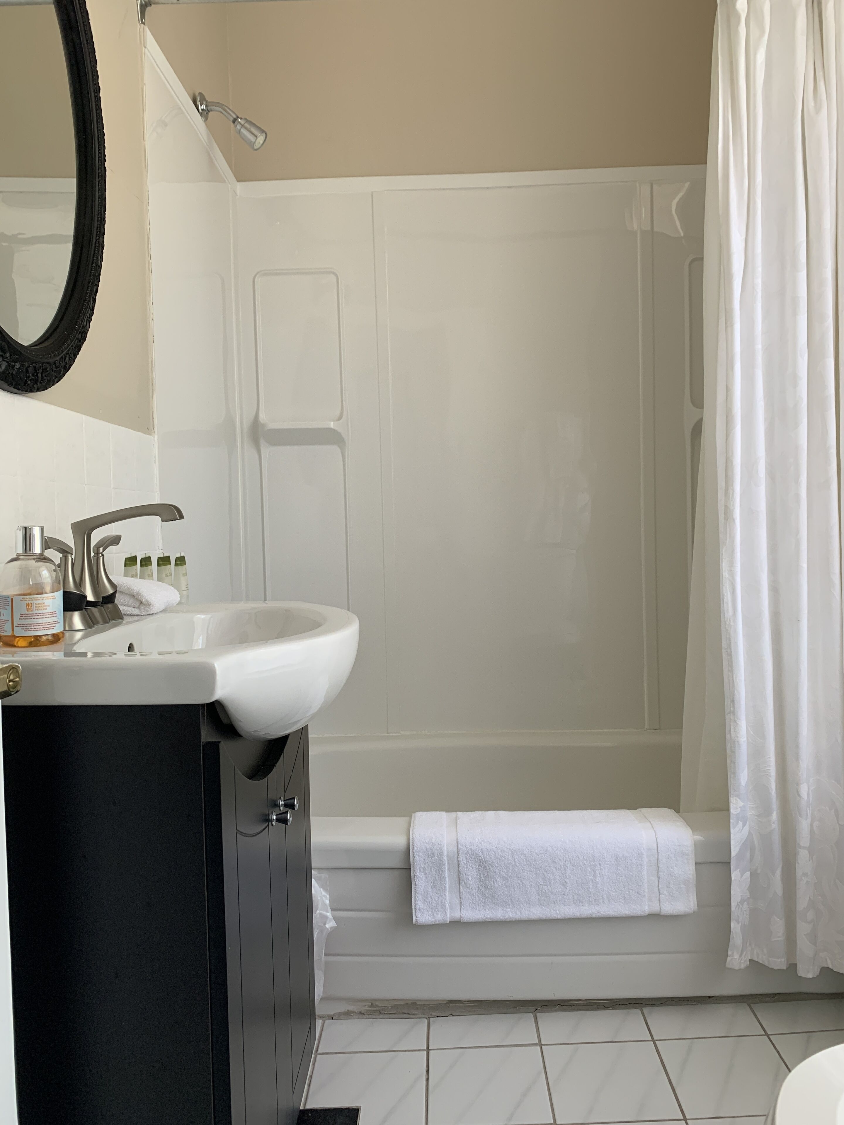 Une salle de bain avec un lavabo blanc, un meuble noir et un rideau de douche.