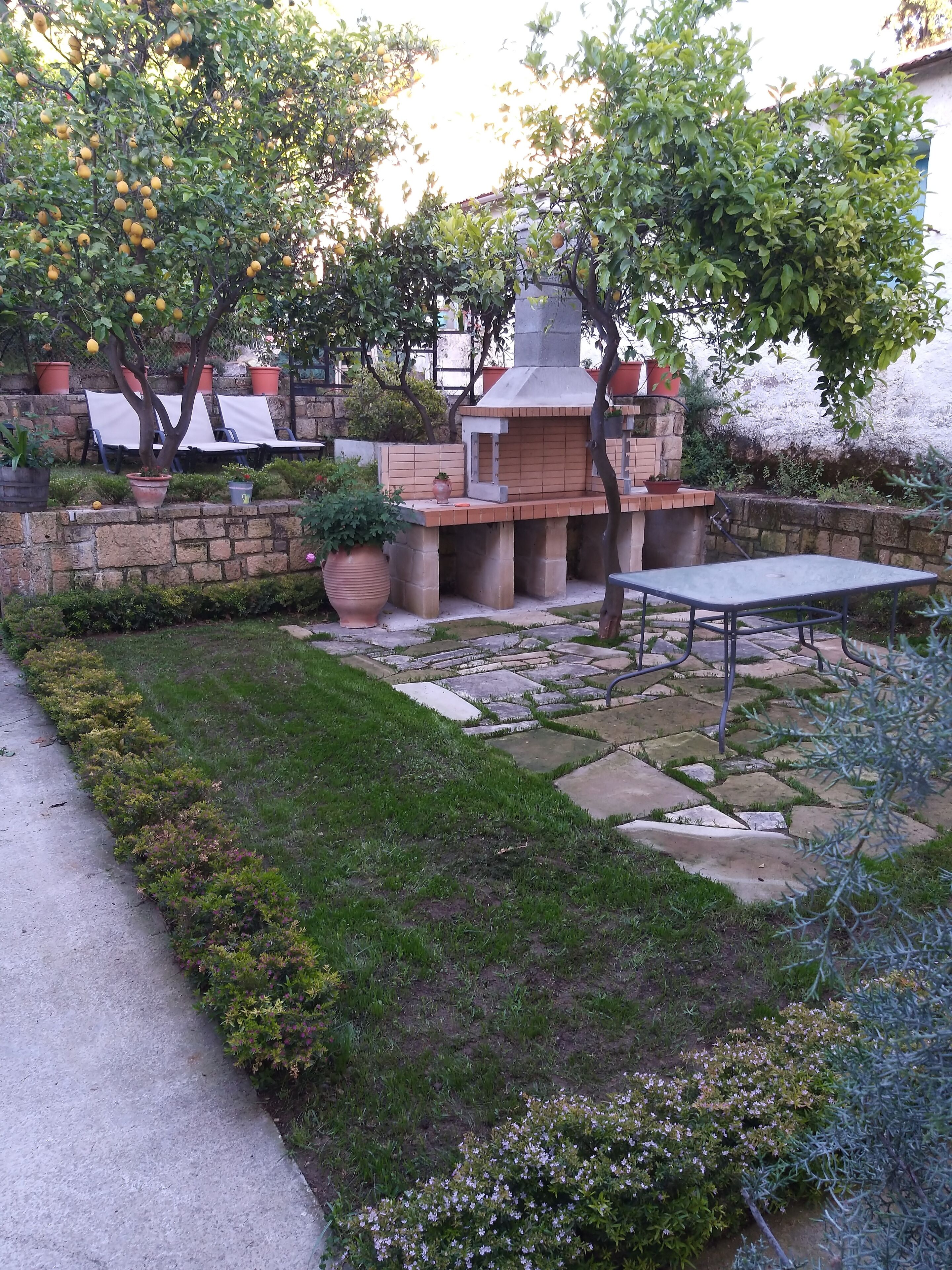 A patio area with a stone barbecue, seating, and potted plants.