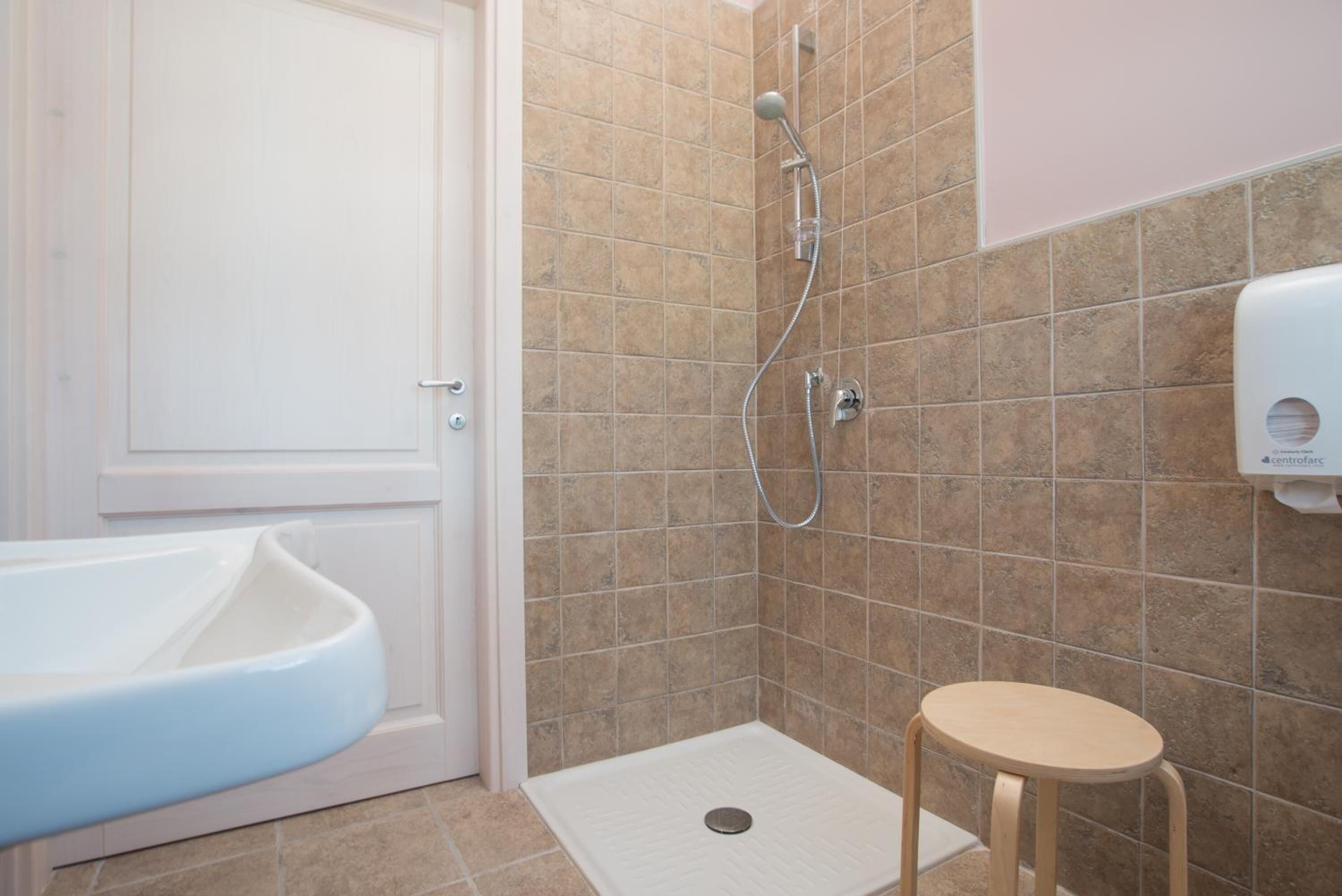 Ein Badezimmer mit einem weißen Waschbecken, einer Dusche inklusive Handbrause und einer Toilette.