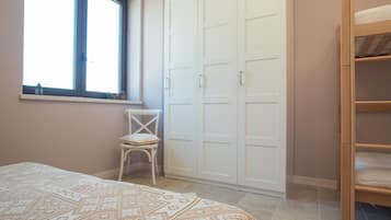 A bedroom with a bed, a chair, a wardrobe, and a window.