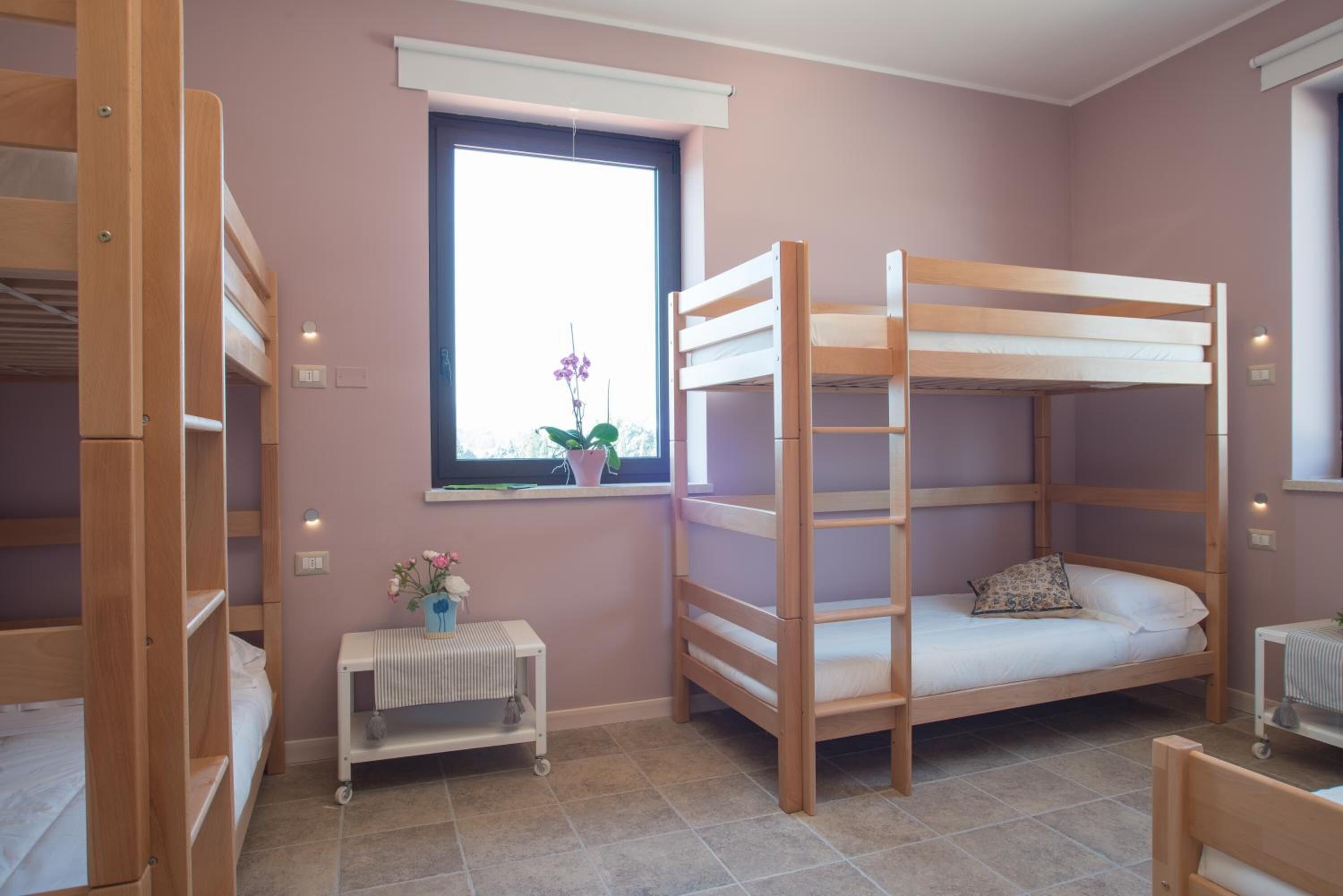 Un dormitorio con literas, una ventana con vistas y una pequeña mesa con una planta.