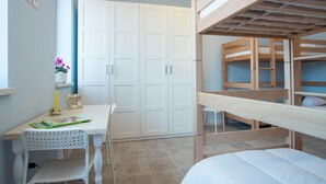 A bedroom with bunk beds, a white desk with a chair, a wardrobe, and a small table with a vase of flowers. - Fattoria Didattica La Collina Incantata (Narni)
