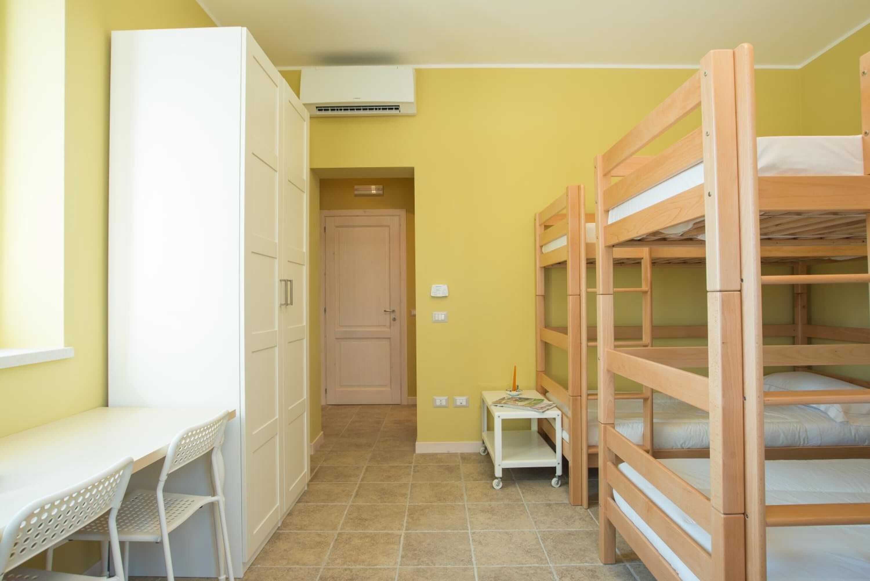A room with bunk beds, a desk, and a chair.