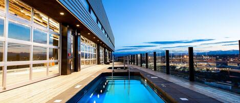 A swimming pool with a view of a cityscape at dusk.