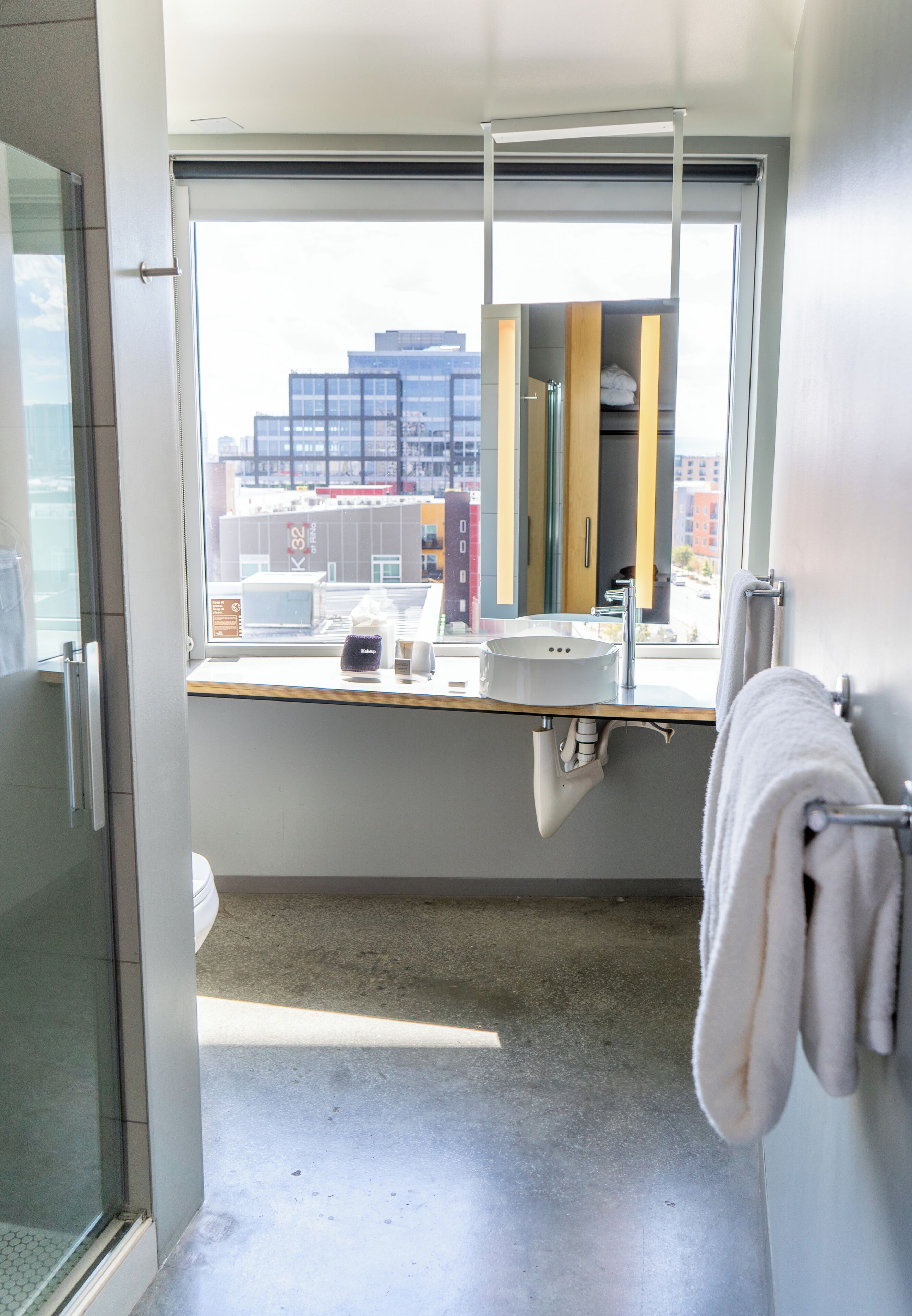 A modern bathroom with a large window, a sink, and a towel rack.
