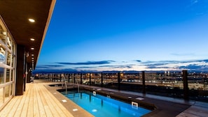A pool area with a view of a cityscape at dusk. - The Source Hotel (Denver)