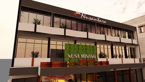 Un hotel llamado Nusa Minang con una fachada moderna, ventanas amplias y un jardín vertical verde.