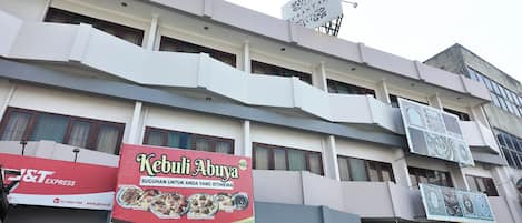 Un edificio de varios pisos con un llamativo letrero rojo y blanco del restaurante Kebuli Abaya, que muestra imágenes de platos.