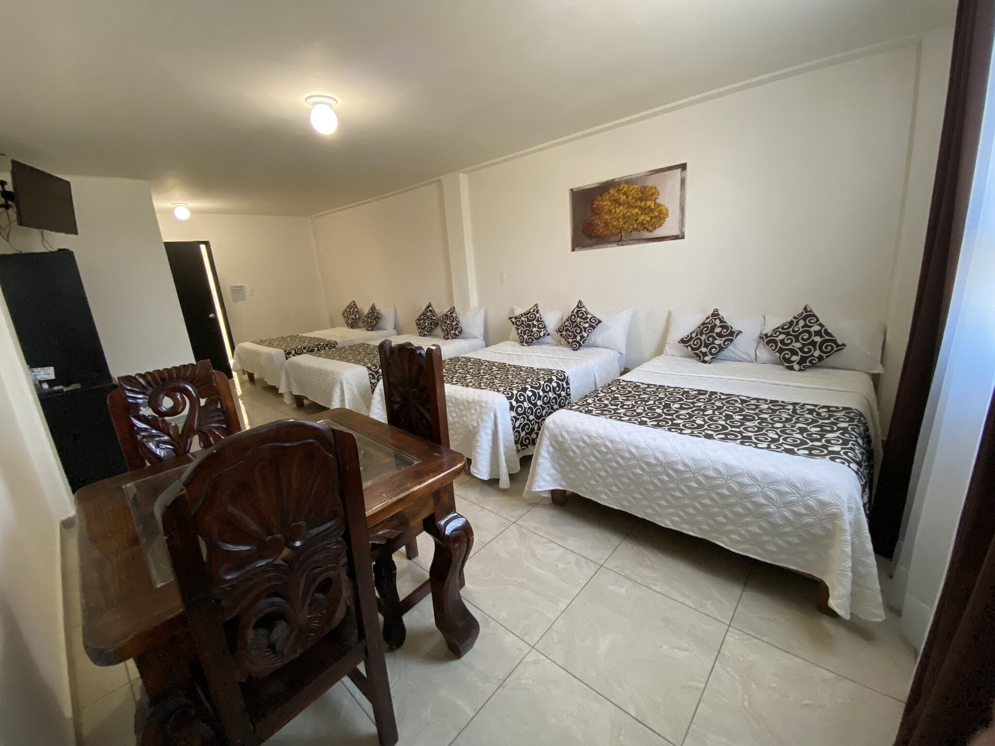 Habitación de hotel con tres camas, una mesa de comedor y sillas.