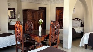 Een hotelkamer met een bed, een eettafel met stoelen, een spiegel en een kledingkast.