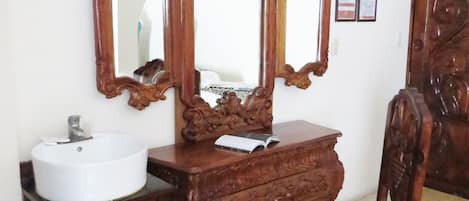 A wooden vanity with a white sink, a mirror, and a chair.