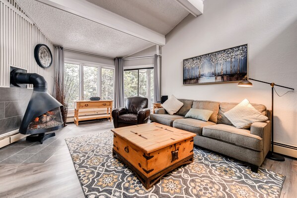 A living room with a fireplace, a sofa, a coffee table, and a painting on the wall.
