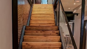 Un escalier en bois avec une rampe en métal, menant à l’étage supérieur.