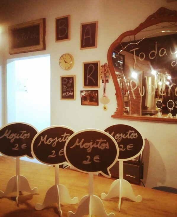 A restaurant interior with chalkboard signs indicating prices for dishes, a wall clock, and framed pictures.