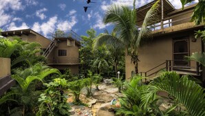 Un patio con un sendero de piedra, palmeras y una escalera que lleva a un balcón.