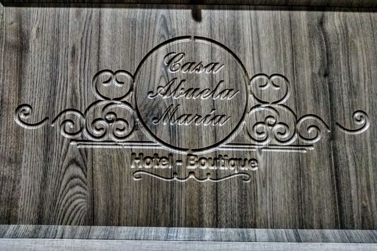 Un panel de madera con texto en relieve que dice 'Casa Abuela Maria Hotel Boutique'.