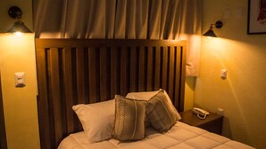 Ein Hotelzimmer mit einem Holzkopfteil, zwei Nachttischlampen, einem Telefon und einem Bett mit weißer Bettwäsche und dekorativen Kissen.