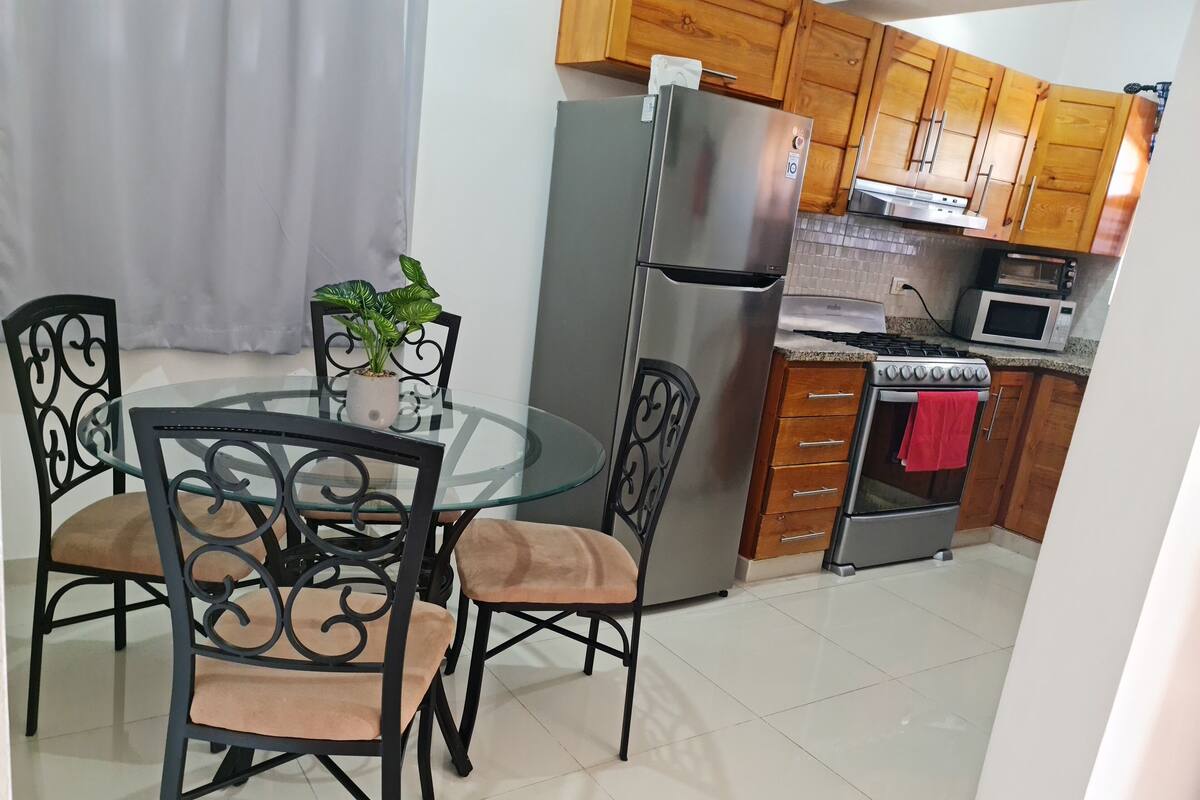 A compact kitchen with a refrigerator, microwave, stove, and wooden cabinets.