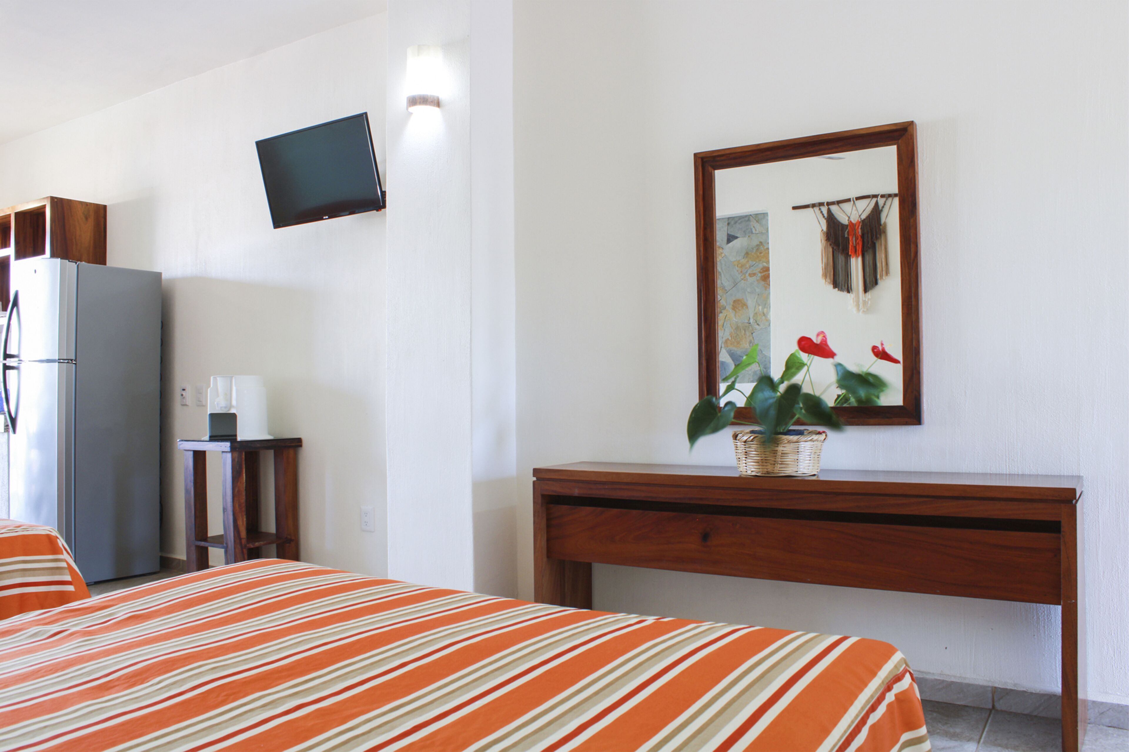 Ein Hotelzimmer mit Bett, Schreibtisch, Fernseher und Kühlschrank.