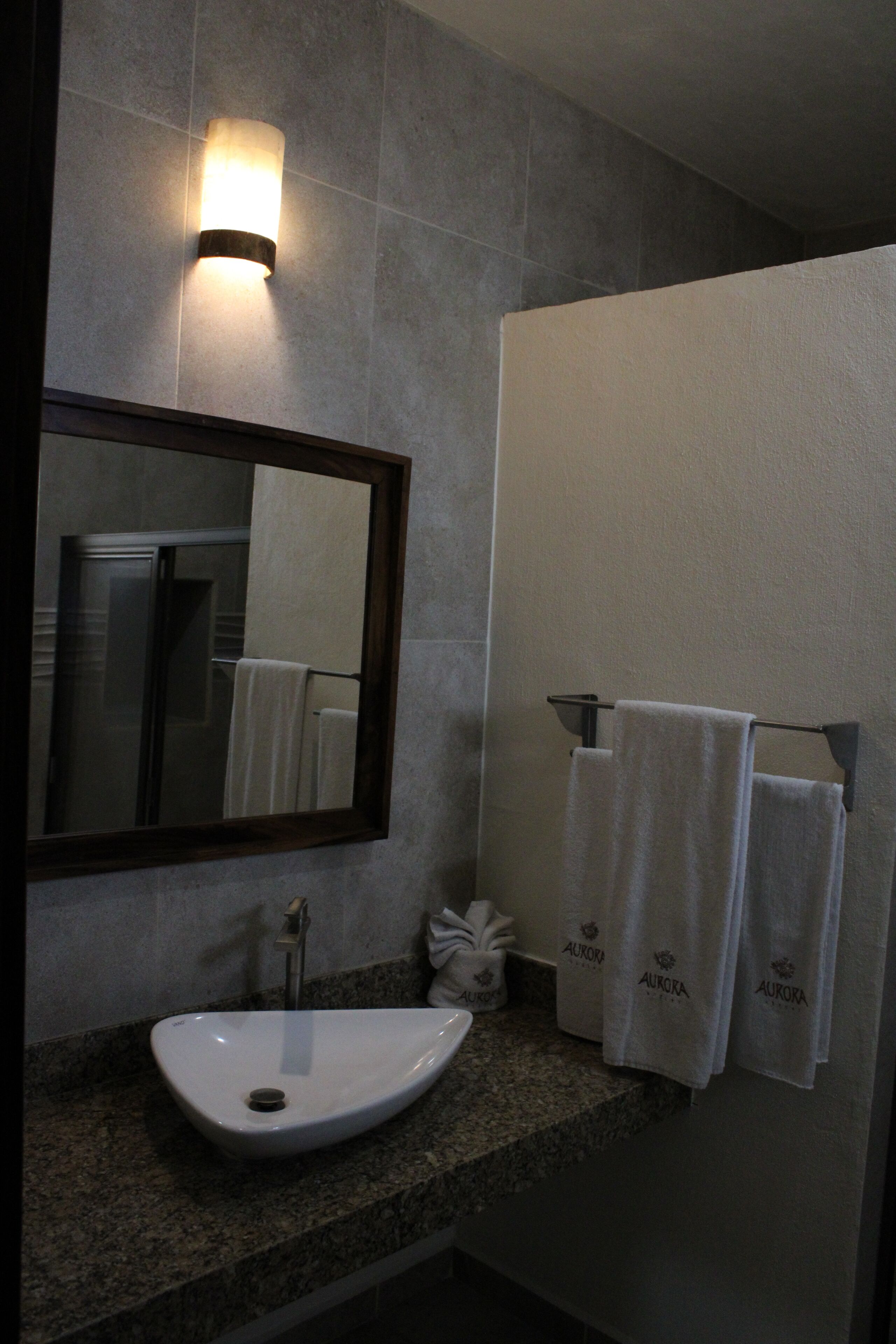 A bathroom with a granite countertop, a white sink, a mirror, and two towels hanging on a rack.