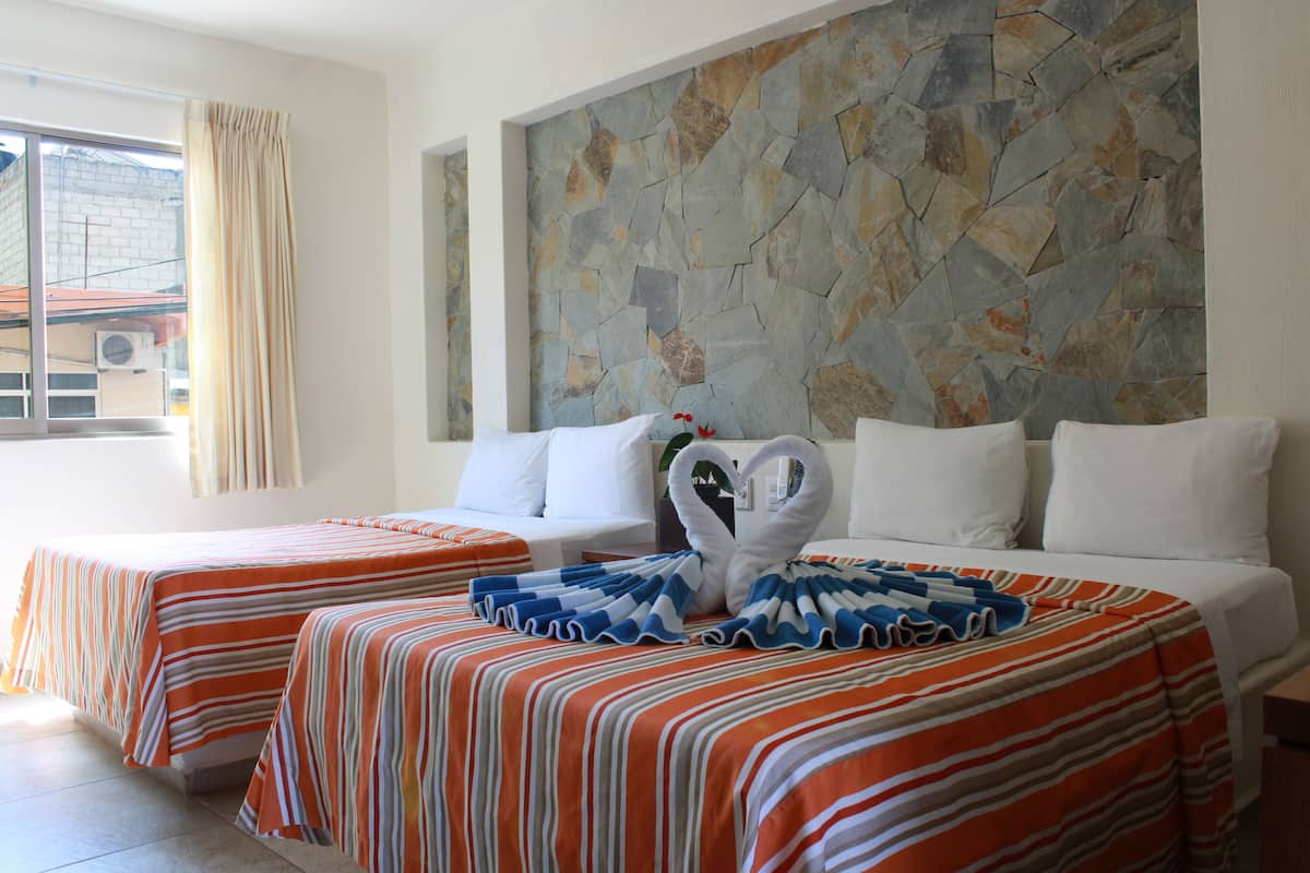 A hotel room with two beds, a stone wall, and a window with curtains.