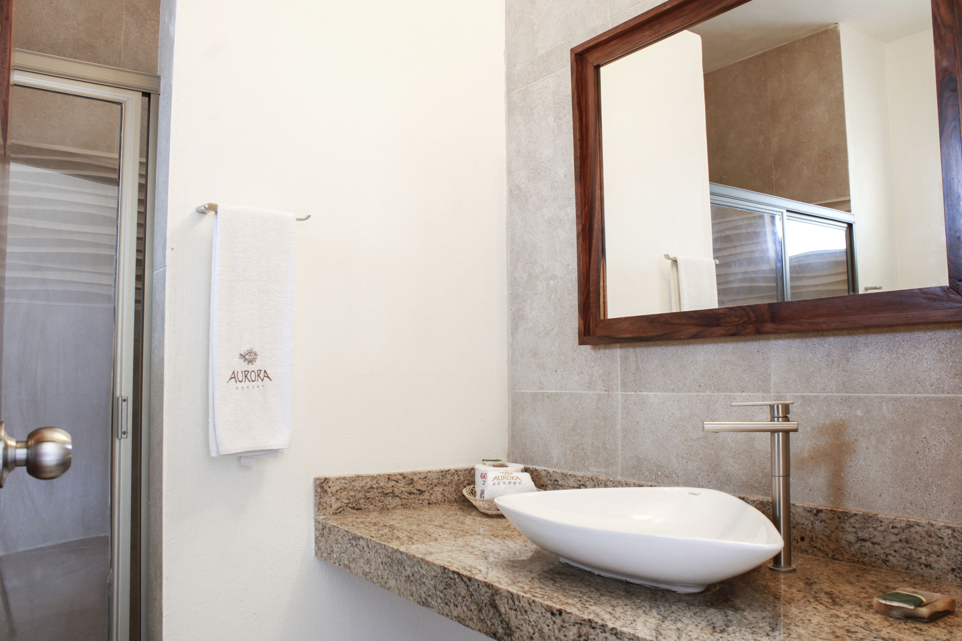 A bathroom with a white sink, a marble countertop, a towel hanging on the wall, and a mirror above the sink.