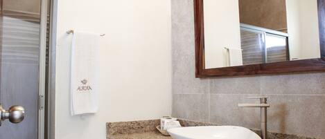 A bathroom with a white sink, a marble countertop, a towel hanging on the wall, and a mirror above the sink.
