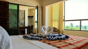 Habitación de hotel con una cama, vista a palmeras y una ventana con cortinas.
