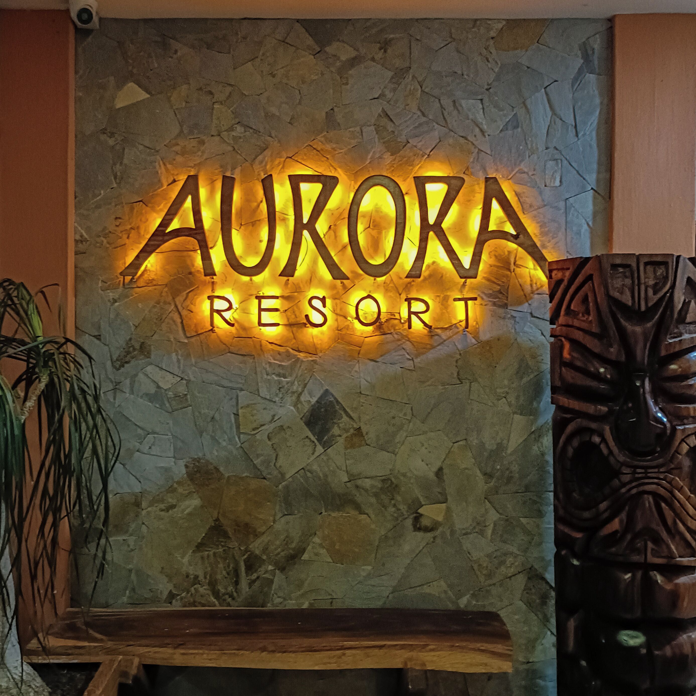 A stone wall with a neon sign reading "AURORA RESORT".