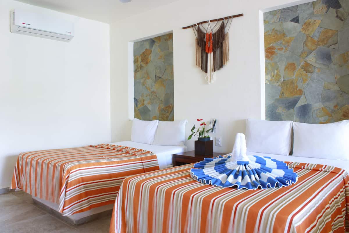 A hotel room with two beds, a stone wall mural, a wall-mounted air conditioner, and a decorative macrame piece.