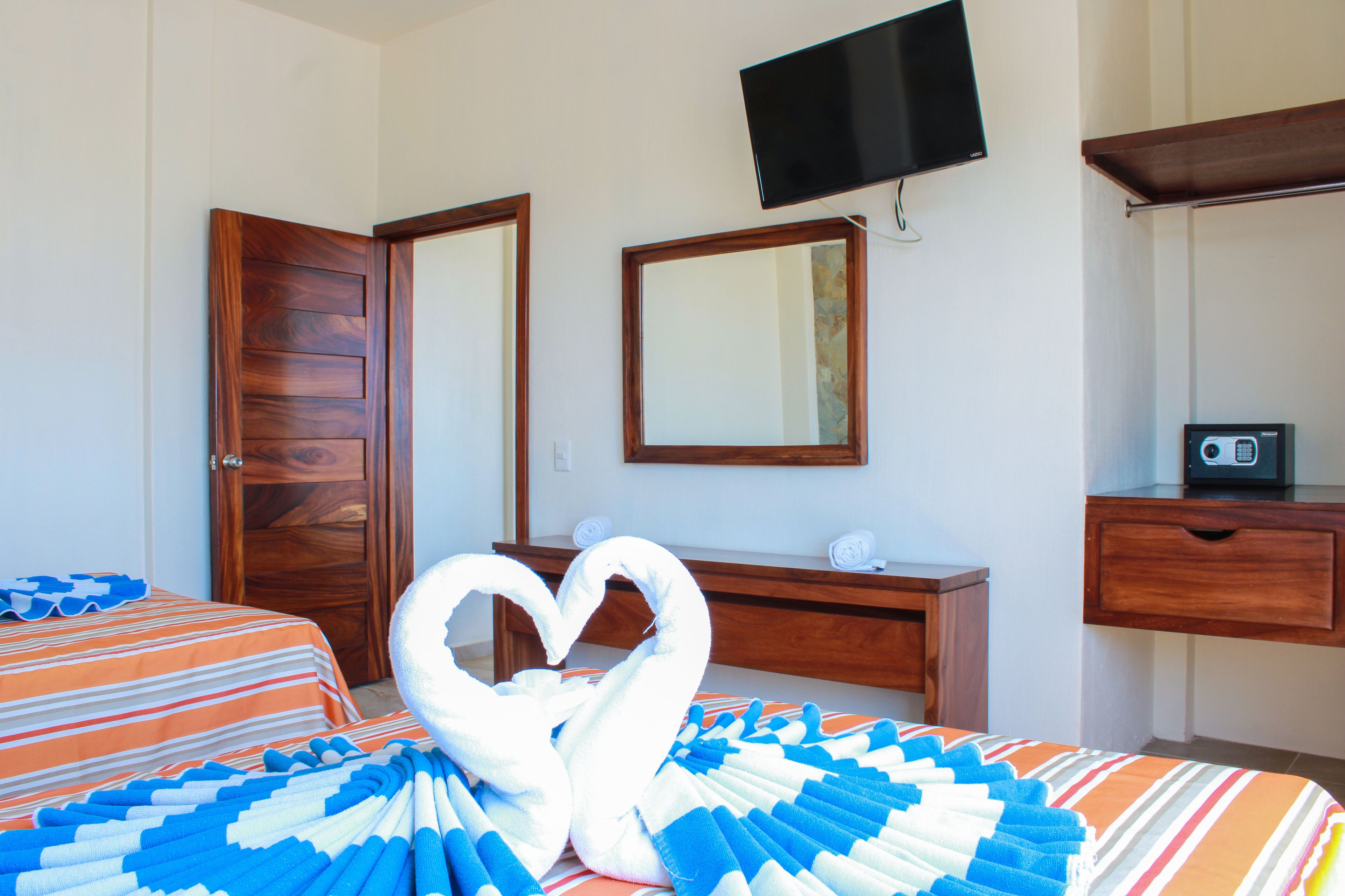 A hotel room with two beds, a wooden dresser, a television mounted on the wall, and a radio on the dresser.
