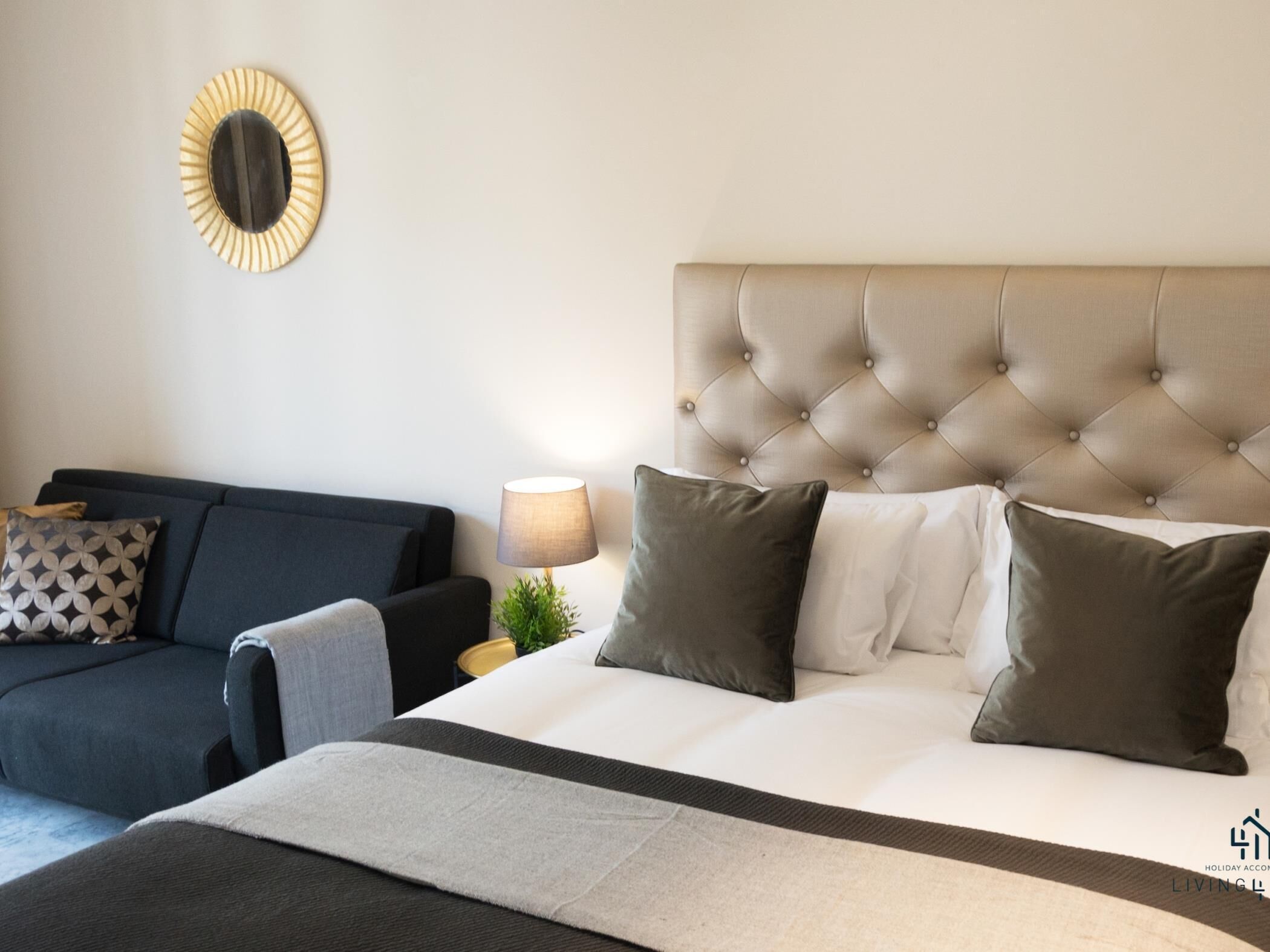 Ett hotellrum med en säng, en soffa, en lampa och en väggdekoration.