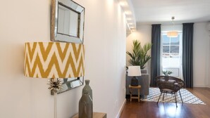 A modern living room with a sofa, a chair, a lamp, and a decorative mirror. - Atico MarinaLiving4malaga (Málaga)
