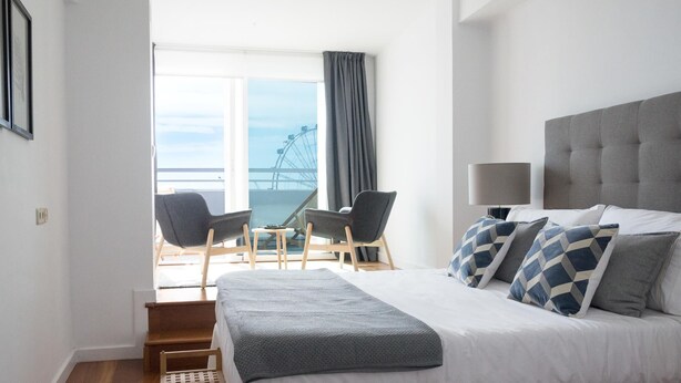 A hotel room with a bed, a chair, a table, and a view of a Ferris wheel. - Atico MarinaLiving4malaga (Málaga)