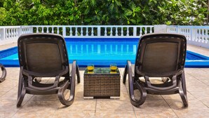 Two chairs facing a pool with a white balustrade and lush greenery in the background. - VILLA PATIENTLY WAITING IS A STUNNING NORTH COAST JAMAICAN GEM A DIAMOND RENTAL (Ocho Rios)