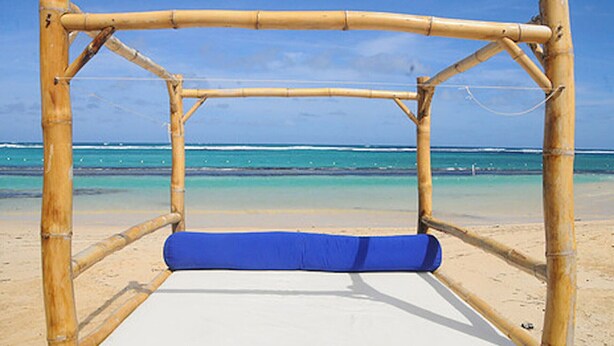 A bamboo-framed bed with a blue mattress on a sandy beach with clear turquoise water in the background. - VILLA PATIENTLY WAITING IS A STUNNING NORTH COAST JAMAICAN GEM A DIAMOND RENTAL (Ocho Rios)
