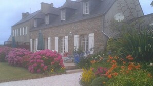 Ein Steinhaus mit Kiesweg und einem Garten mit verschiedenen Blumen.