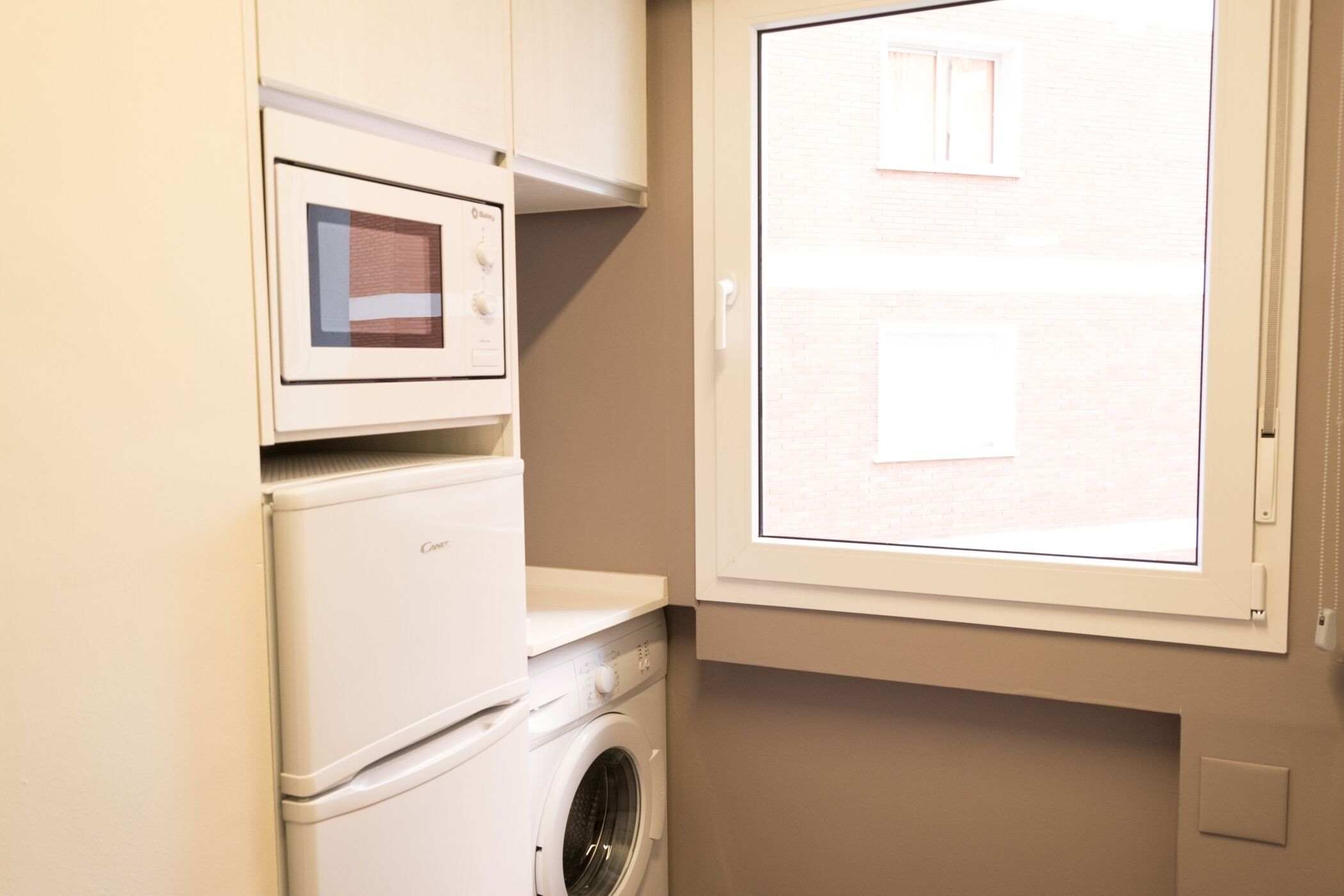A compact laundry room with a washing machine, dryer, and microwave.