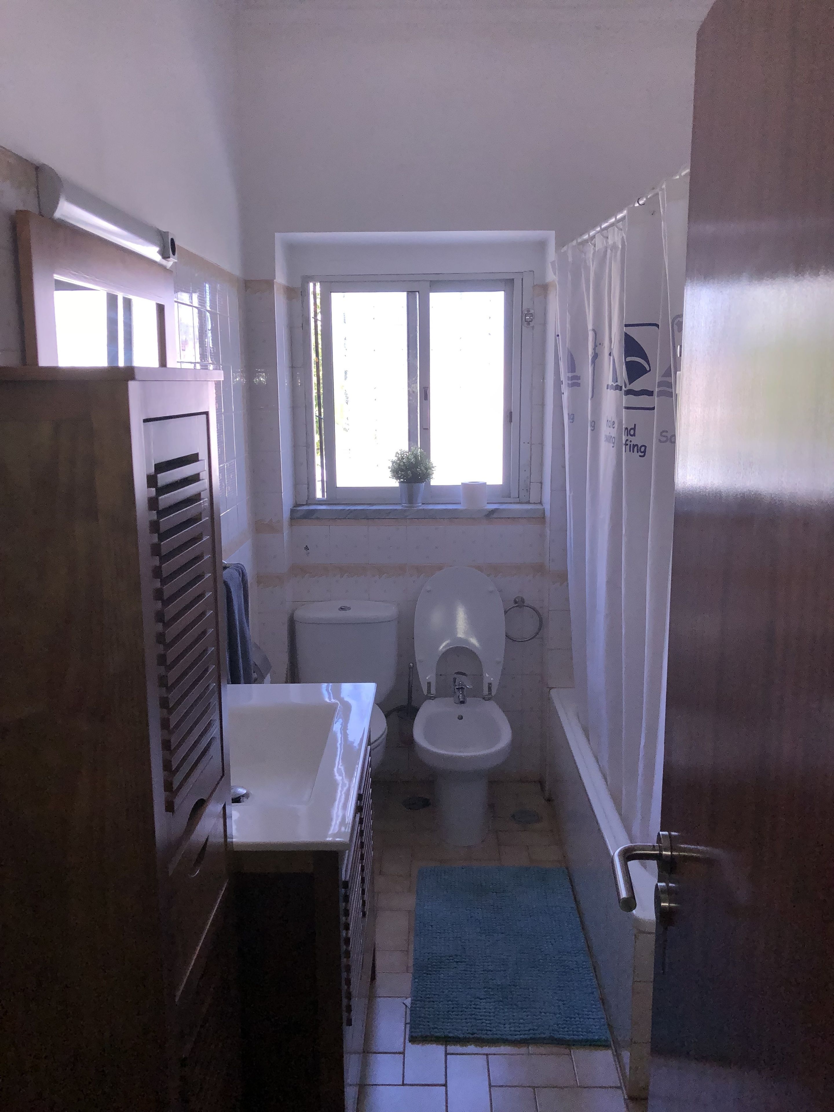 A compact bathroom with a toilet, sink, and window.