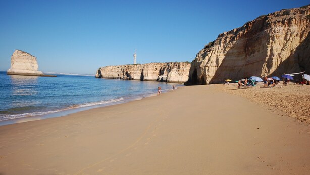 A beach with clear blue water, a lighthouse, and rocky cliffs. - Luxury Gated Villa | Private Pool | Sesmarias near Carvoeiro (Carvoeiro)