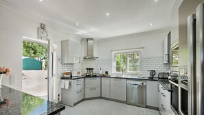 A modern kitchen with white cabinets, a stainless steel range hood, and a dishwasher. - Luxury Gated Villa | Private Pool | Sesmarias near Carvoeiro (Carvoeiro)