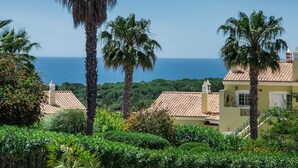 A coastal villa with a view of the sea, surrounded by lush greenery and palm trees. - Luxury Gated Villa | Private Pool | Sesmarias near Carvoeiro (Carvoeiro)