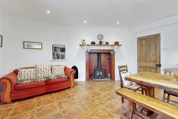 Una sala de estar con sofá, chimenea, mesa de comedor y estantería.