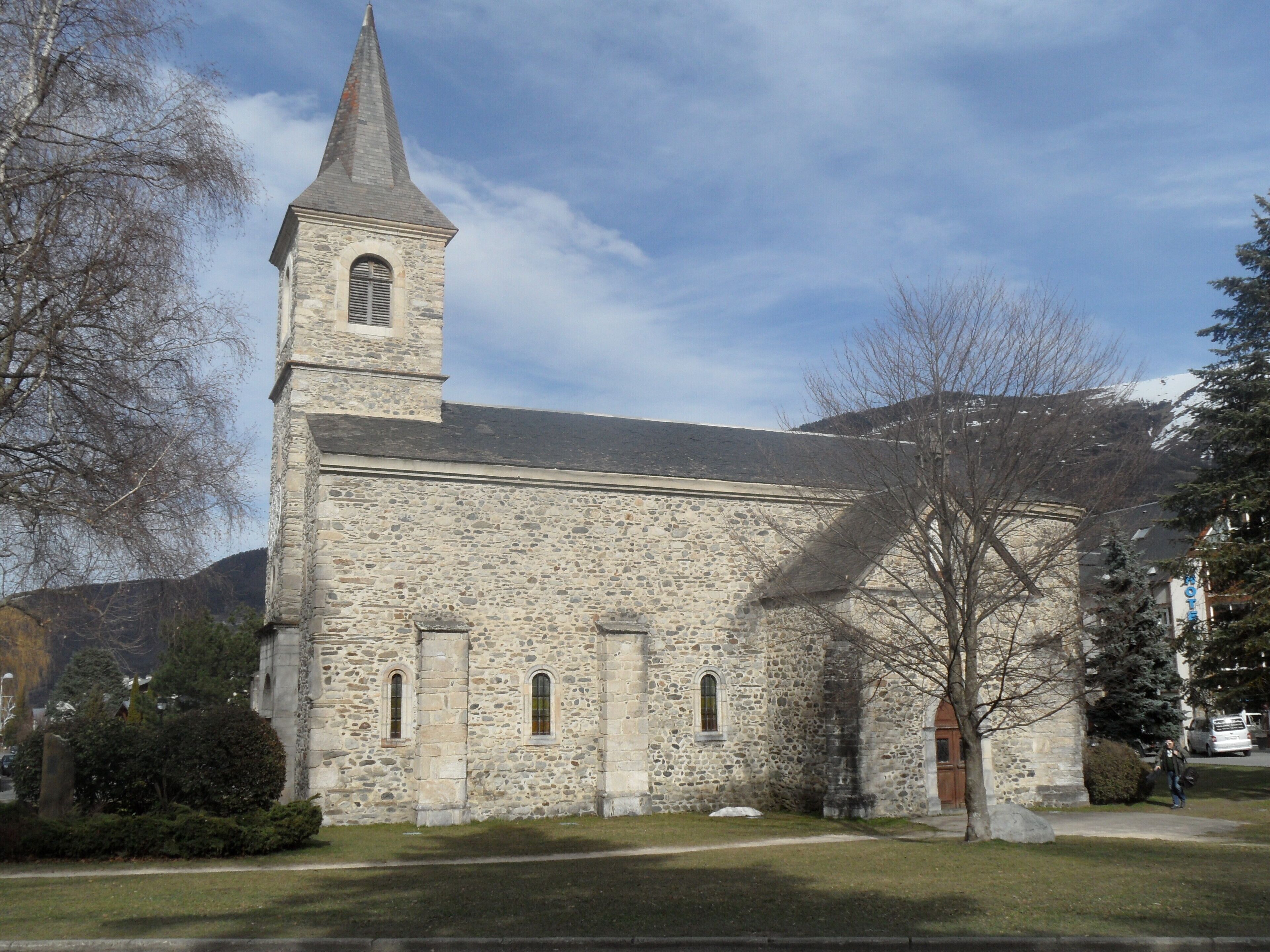 Eine Steinkirche mit einem hohen Kirchturm und Rundbogenfenstern.