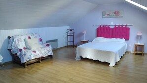 A bedroom with a wooden floor, a bed with a white bedspread, a chair with a floral cover, a pink curtain, and a small table with a lamp. - stone house Saint Léger de Peyre (Saint-Léger-De-Peyre)