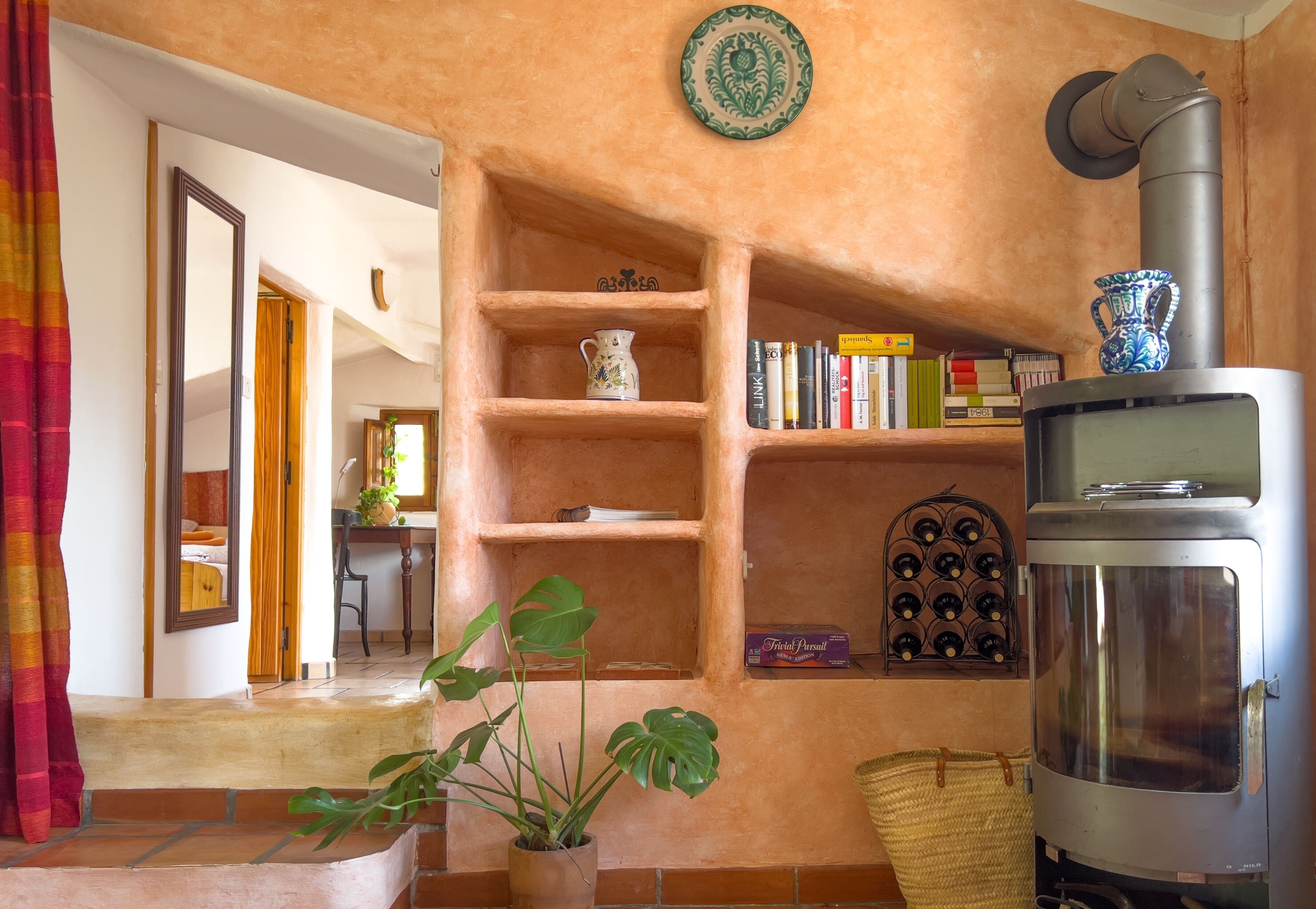 Una sala de estar acogedora con chimenea, estanterías llenas de libros y adornos, una planta en maceta y una cesta de mimbre.